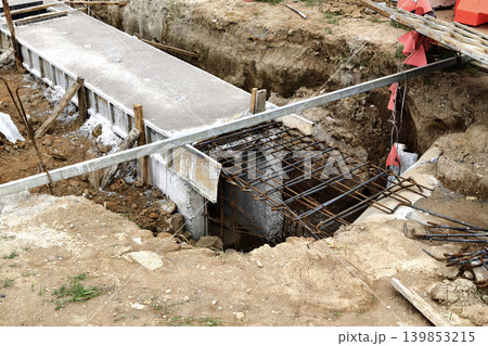Narrow ditch with reinforcement, waterproof concrete trench bounded by soil and support stakes 139853215