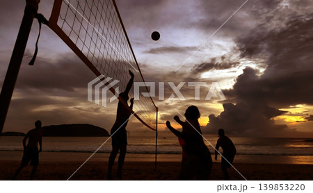 Young people playing beach volleyball by the ocean at sunset Young people playing beach volleyball by the ocean at sunset 139853220