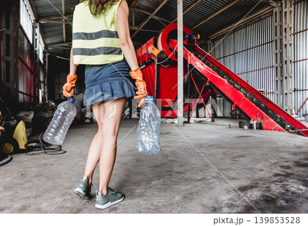 Woman-volunteer sorting trash at modern recycling plant. Woman-volunteer sorting trash at modern recycling plant. 139853528