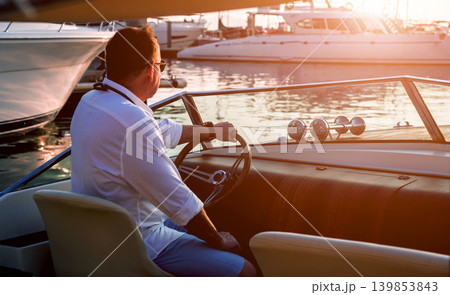 Young man on sailing yacht. Hands hold steering wheel Young man on sailing yacht. Hands hold steering wheel 139853843