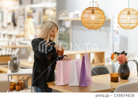 Woman smiling while arranging purchases in shopping bags Woman smiling while arranging purchases in shopping bags 139854816