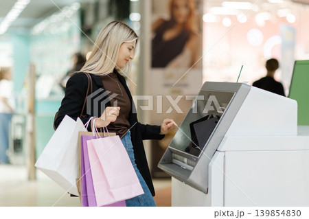 Woman withdrawing cash from ATM after shopping 139854830
