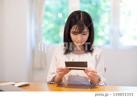 デスクで通帳を眺める日本人の若い女性 139855355