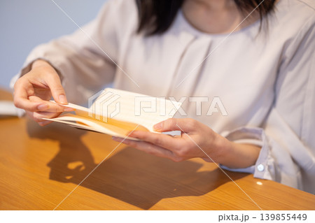 通帳のページをめくる女性の手元のクローズアップ 139855449