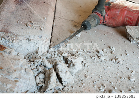 Breaking concrete floor with electric jackhammer close up 139855683
