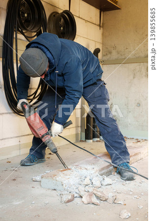 Worker demolishing concrete floor during home renovation Worker demolishing concrete floor during home renovation 139855685