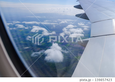 Looking from the airplane window with stunning skyscapes and landscape with airplane wing. Travel and transportation concept. Looking from the airplane window with stunning skyscapes and landscape with airplane wing. Travel and transportation concept. 139857423
