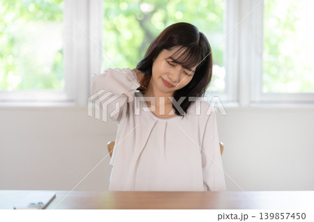 肩に手を当てて眉をしかめる日本人の若い女性 肩に手を当てて眉をしかめる日本人の若い女性 139857450
