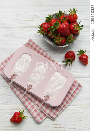 Making homemade strawberry ice cream popsicles in silicone mold 139858327