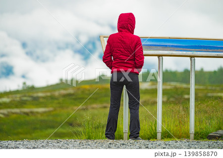 Tourist woman in mountains near information board. Tourist woman in mountains near information board. 139858870