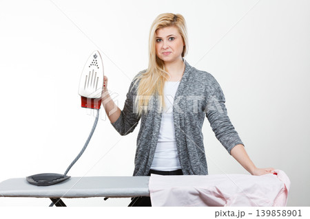 Woman holding iron about to do ironing Woman holding iron about to do ironing 139858901