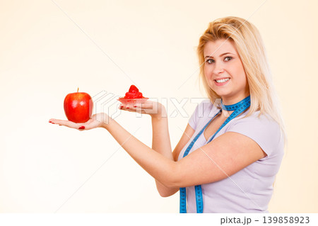 Woman with measuring tape choosing what to eat Woman with measuring tape choosing what to eat 139858923