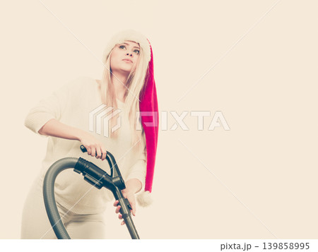 Girl in santa helper hat with vacuum cleaner Girl in santa helper hat with vacuum cleaner 139858995