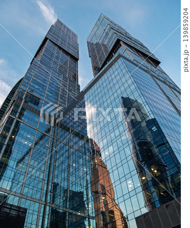 Two towering modern glass buildings dominate the frame, reaching high into the bright blue sky Two towering modern glass buildings dominate the frame, reaching high into the bright blue sky 139859204