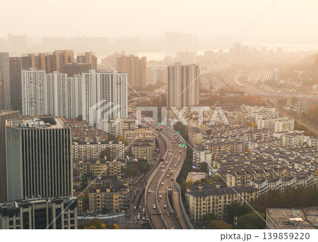 A major highway filled with vehicles stretches through a large urban area featuring modern high-rise buildings and older residential blocks A major highway filled with vehicles stretches through a large urban area featuring modern high-rise buildings and older residential blocks 139859220