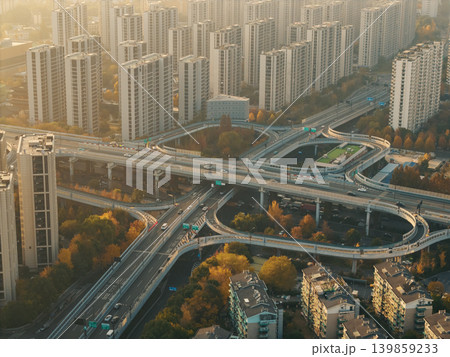 Cars move on a multi-level highway interchange cutting through a city filled with numerous tall residential and commercial structures Cars move on a multi-level highway interchange cutting through a city filled with numerous tall residential and commercial structures 139859233