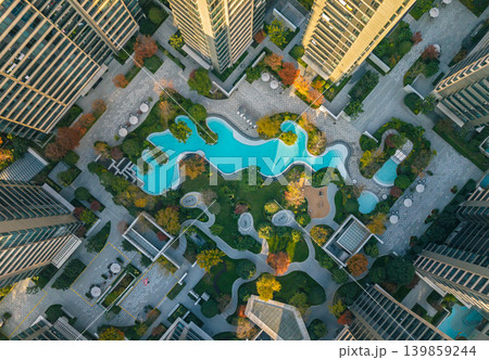 Overhead view of a large urban residential complex. Numerous modern high-rise buildings surround a park with bright blue swimming pools Overhead view of a large urban residential complex. Numerous modern high-rise buildings surround a park with bright blue swimming pools 139859244