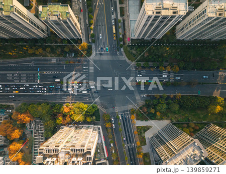 Busy city intersection from above with cars, a red bus, and other vehicles navigating multi-lane roads. Pedestrians cross the street 139859271