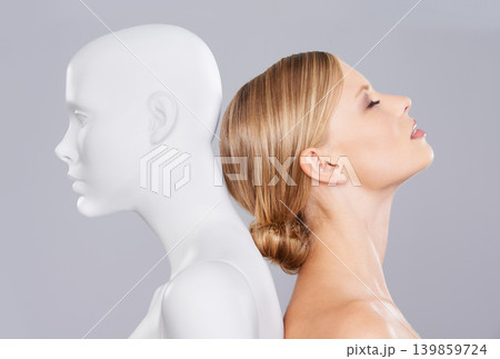 Studio, girl and mannequin with perfect beauty versus artificial standard, identity and facial wellness. Woman, doll and face in profile for cosmetics, plastic surgery or makeup on grey background. Studio, girl and mannequin with perfect beauty versus artificial standard, identity and facial wellness. Woman, doll and face in profile for cosmetics, plastic surgery or makeup on grey background. 139859724