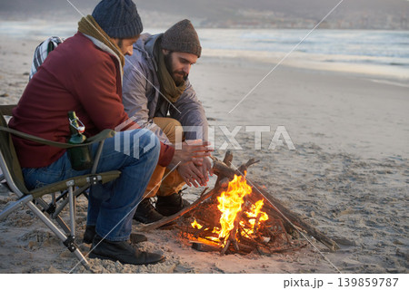 Campfire, friends and adventure with men by the beach at sunset with vacation and camping. Ocean, outdoor and together with travel and people in a trip and journey with fire and conversation by sea 139859787
