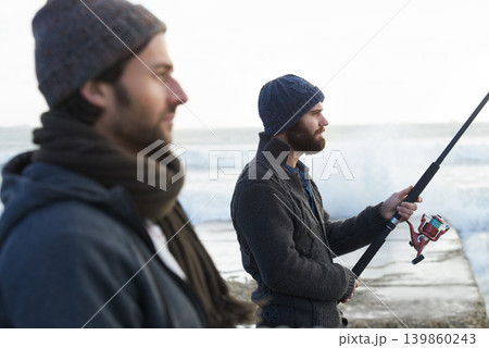 People, fishing and friends for bonding at beach, relaxing and casting a line by ocean waves. Men, fisherman and together on vacation or holiday, hobby and gear by water and support on adventure 139860243