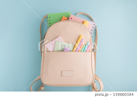 Pastel school supplies into backpack on blue background Pastel school supplies into backpack on blue background 139860384