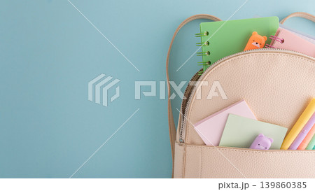 Pastel school supplies into backpack on blue background Pastel school supplies into backpack on blue background 139860385