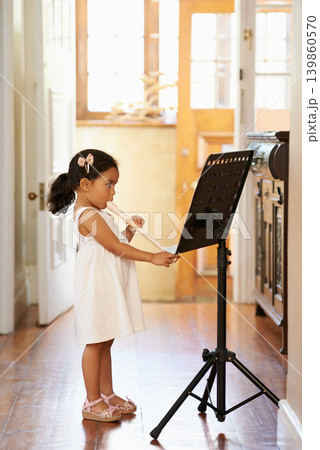 Flute, girl and child playing in home for learning, education and reading music sheet to practice performance. Art, flutist and kid with talent, creative or hobby with instrument for sound at lesson Flute, girl and child playing in home for learning, education and reading music sheet to practice performance. Art, flutist and kid with talent, creative or hobby with instrument for sound at lesson 139860570