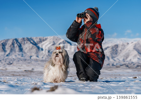 Child with binoculars and shih tzu dog posing on mountains background at winter Child with binoculars and shih tzu dog posing on mountains background at winter 139861555