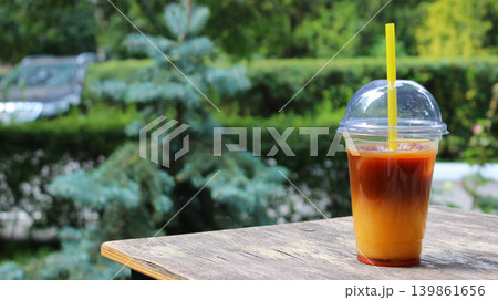 A small table with a cup of iced orange coffee takeaway cocktail in an outdoor cafe 139861656