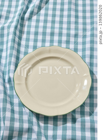 Empty White Ceramic Plate on a Wrinkled Blue Checked Tablecloth. Top View 139862020