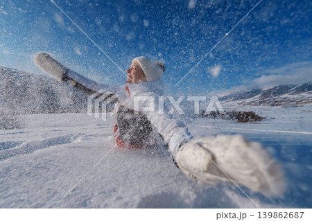 Young smiling woman falling in snow on mountains background at winter season 139862687