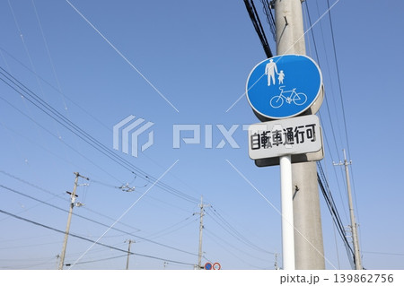 歩道の自転車通行可標識。電柱と青空。自転車通行可能を示す青い看板 歩道の自転車通行可標識。電柱と青空。自転車通行可能を示す青い看板 139862756