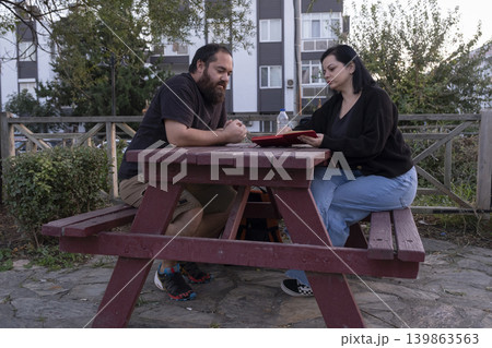 Man and Woman Working Together on Park Bench. Man and Woman Working Together on Park Bench. 139863563