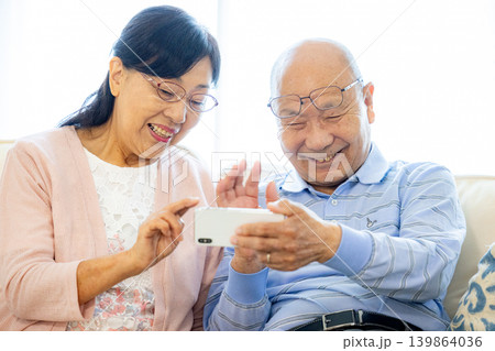 スマホでテレビ電話をするシニア夫婦 スマホでテレビ電話をするシニア夫婦 139864036