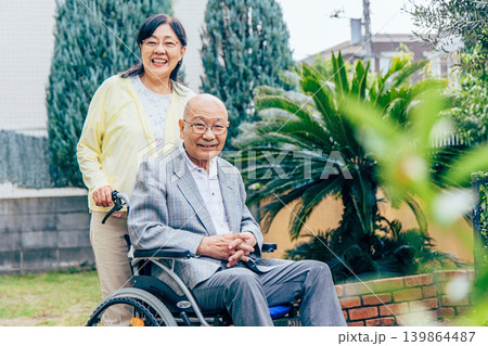 車椅子の高齢者をサポートする妻 車椅子の高齢者をサポートする妻 139864487