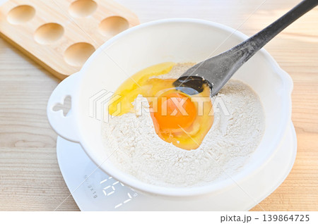 ボウルに入った小麦粉に生卵を加える ボウルに入った小麦粉に生卵を加える 139864725