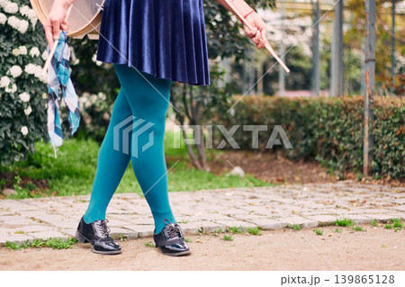 View of legs wearing green tights and a woman's skirt, belonging to a chinchinera, a female street musician who dances and plays her drum in the streets. Chilean heritage, Chilean culture View of legs wearing green tights and a woman's skirt, belonging to a chinchinera, a female street musician who dances and plays her drum in the streets. Chilean heritage, Chilean culture 139865128