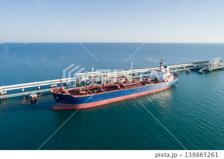 Aerial view of a large oil tanker docked at a pier in the port in process of loading. Aerial view of a large oil tanker docked at a pier in the port in process of loading. 139865261