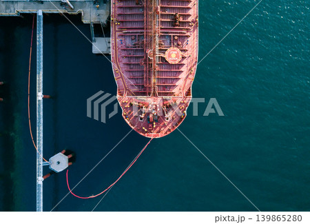 Aerial top down view of a large oil tanker docked at a pier in the port in process of loading. Aerial top down view of a large oil tanker docked at a pier in the port in process of loading. 139865280