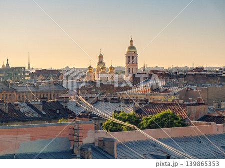 City panorama of St. Petersburg at golden hour. Golden church domes and a tall bell tower rise above historic rooftops. City panorama of St. Petersburg at golden hour. Golden church domes and a tall bell tower rise above historic rooftops. 139865353