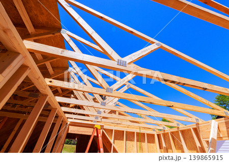 Workers are building wooden roof truss frame with beams supports on construction site Workers are building wooden roof truss frame with beams supports on construction site 139865915