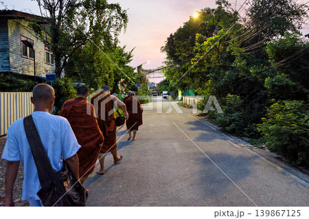 Thai Monks walk on road with bowl to receive food from Buddhist Thai Monks walk on road with bowl to receive food from Buddhist 139867125
