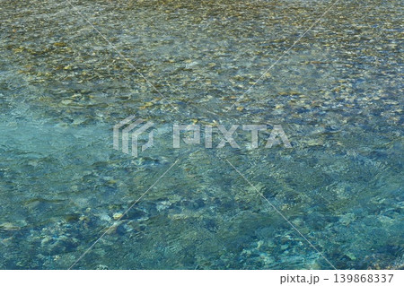 川底の石が透ける青く澄んだ透明度の高い水面 川底の石が透ける青く澄んだ透明度の高い水面 139868337