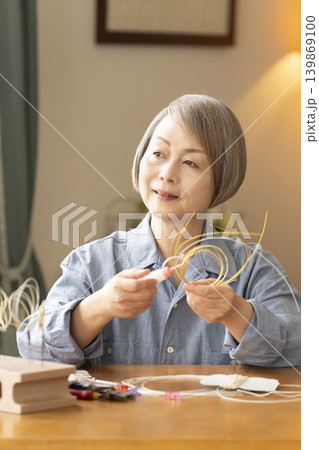 水引で髪飾りを作るシニア女性 水引で髪飾りを作るシニア女性 139869100