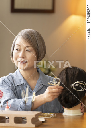 水引で髪飾りを作りマネキンに挿すシニア女性 139869263