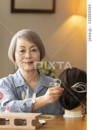 水引で髪飾りを作りマネキンに挿すシニア女性 139869264