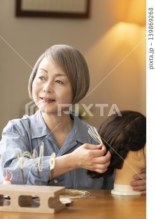 水引で髪飾りを作りマネキンに挿すシニア女性 139869268