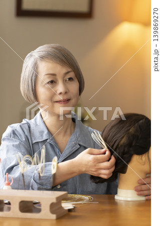 水引で髪飾りを作りマネキンに挿すシニア女性 139869270
