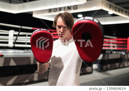 Boxing Trainer Holding Focus Pads Inside the Ring Boxing Trainer Holding Focus Pads Inside the Ring 139869624